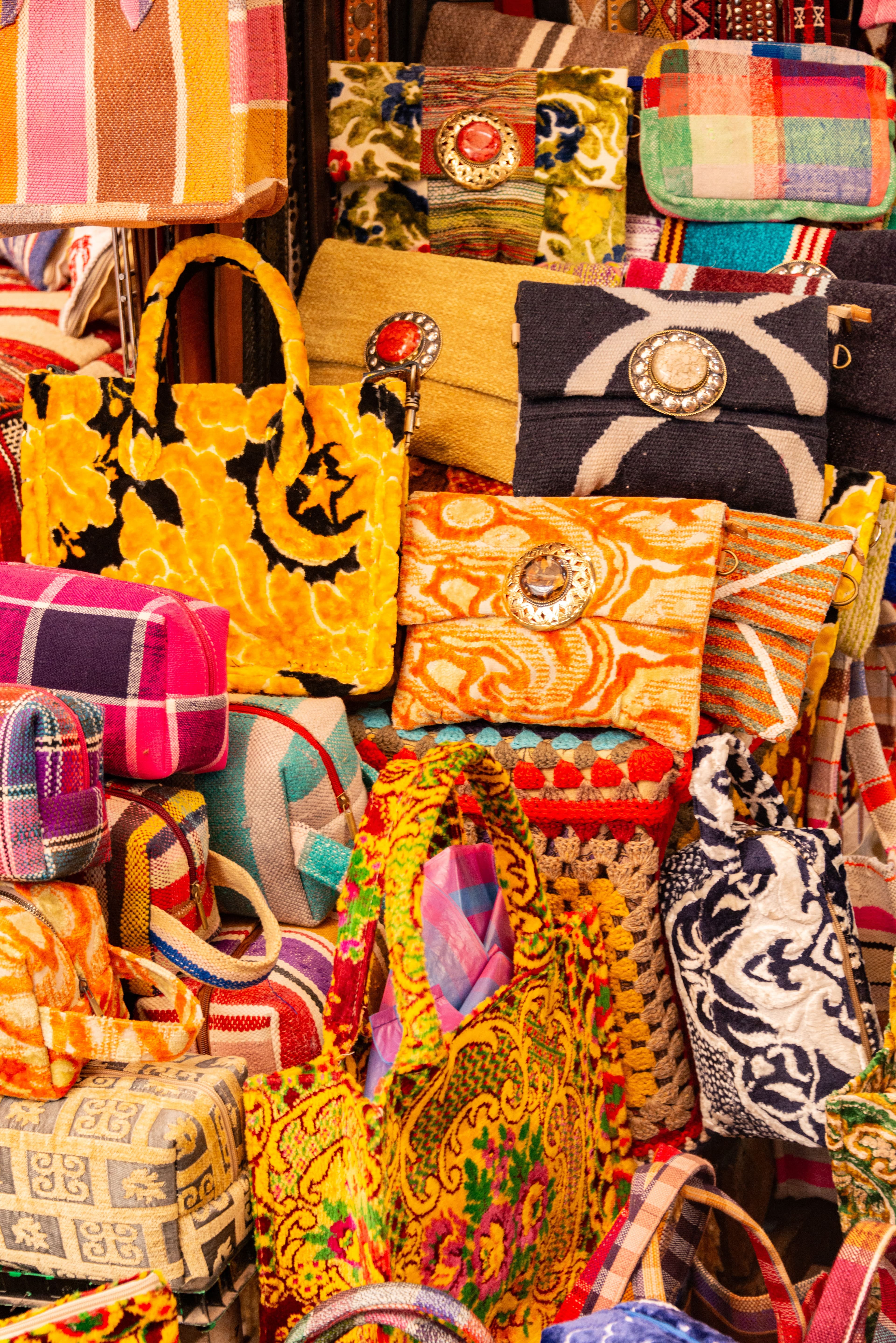 Vibrant collection of handmade handbags on display at a market, showcasing colorful patterns and textures.